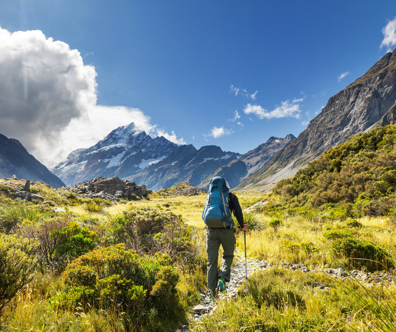 man with blue camping bag and hiking in the mountains